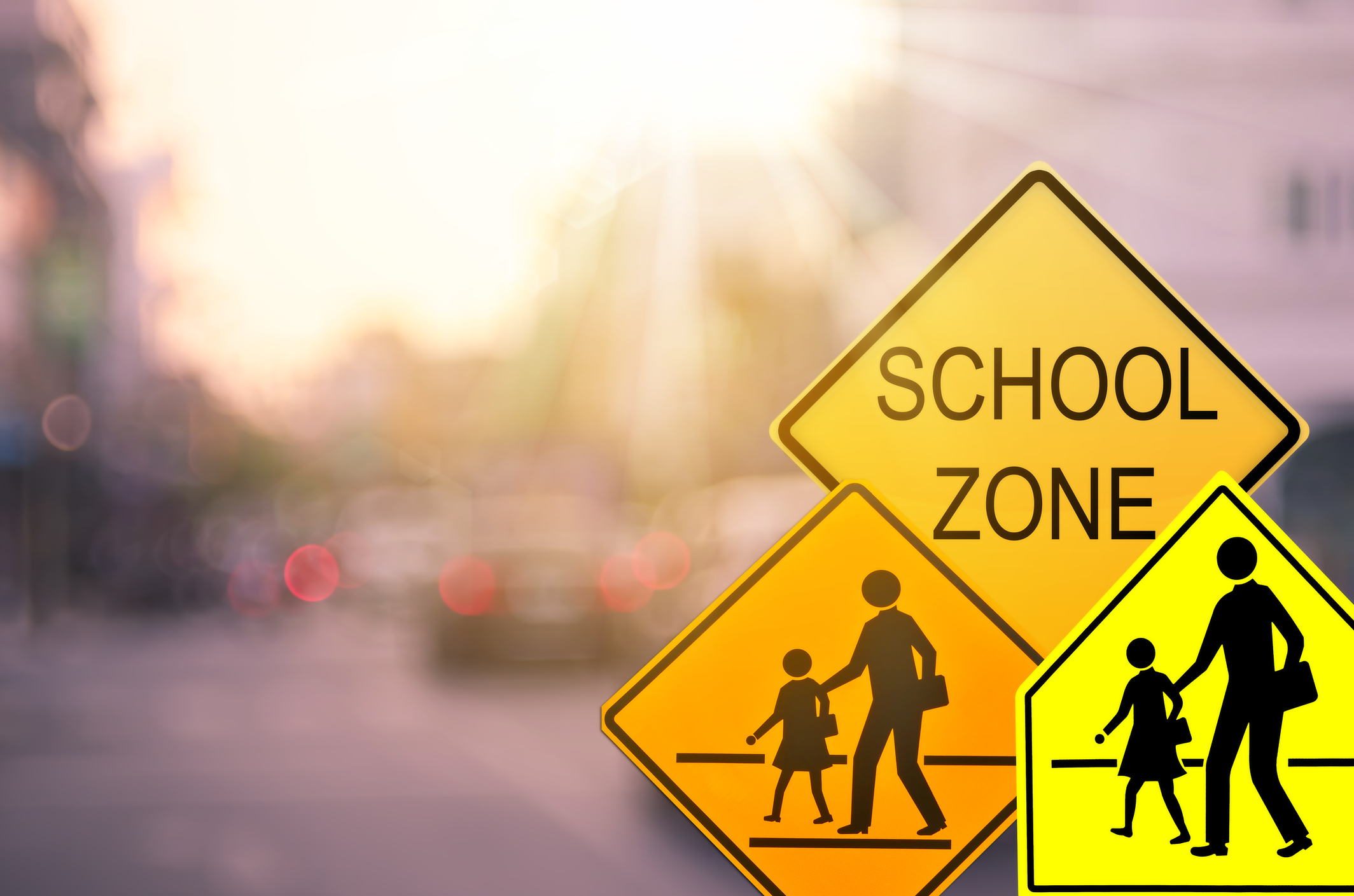 School zone warning sign on blur traffic road with colorful bokeh light abstract background. Copy space of transportation and travel concept. Vintage tone color style. school districts