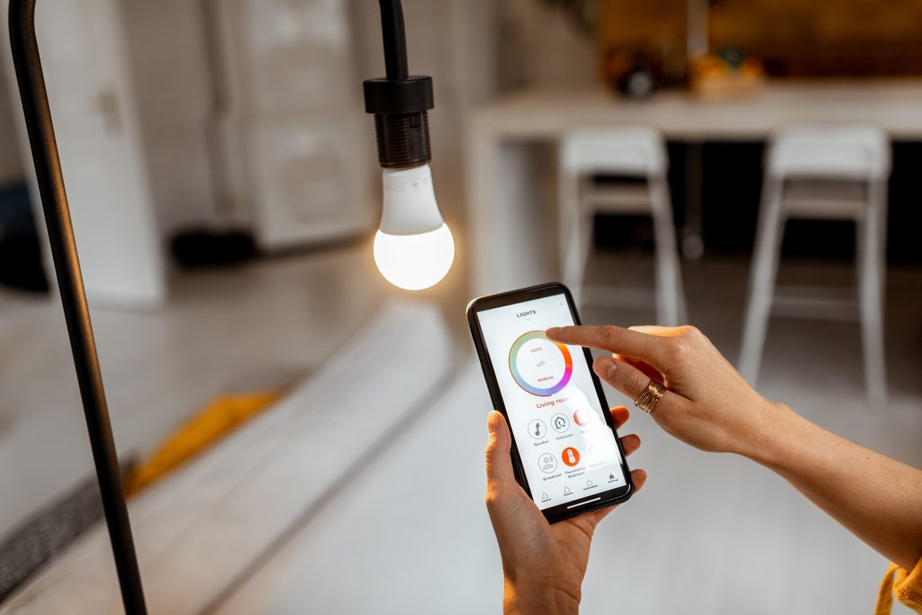 Controlling light bulb temperature and intensity with a smartphone application. Concept of a smart home and managing light with mobile devices, smart home