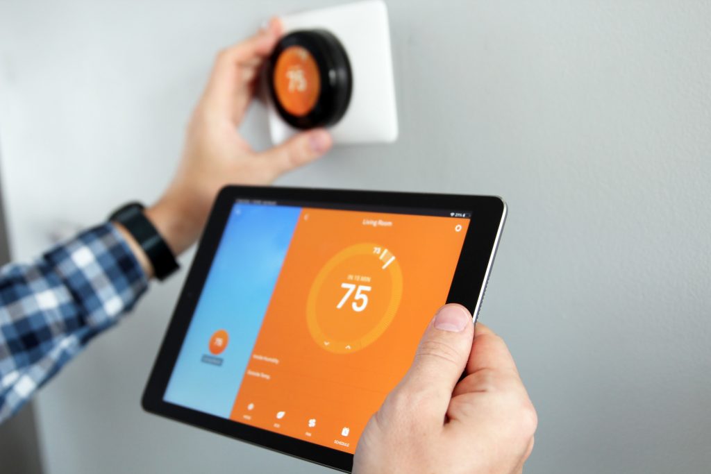 Man is Adjusting a temperature using a tablet with smart home app in modern living room, smart home