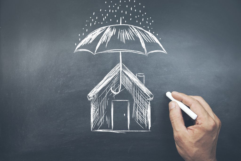 Businessman drawing umbrella over house on checkboard fall safety tips